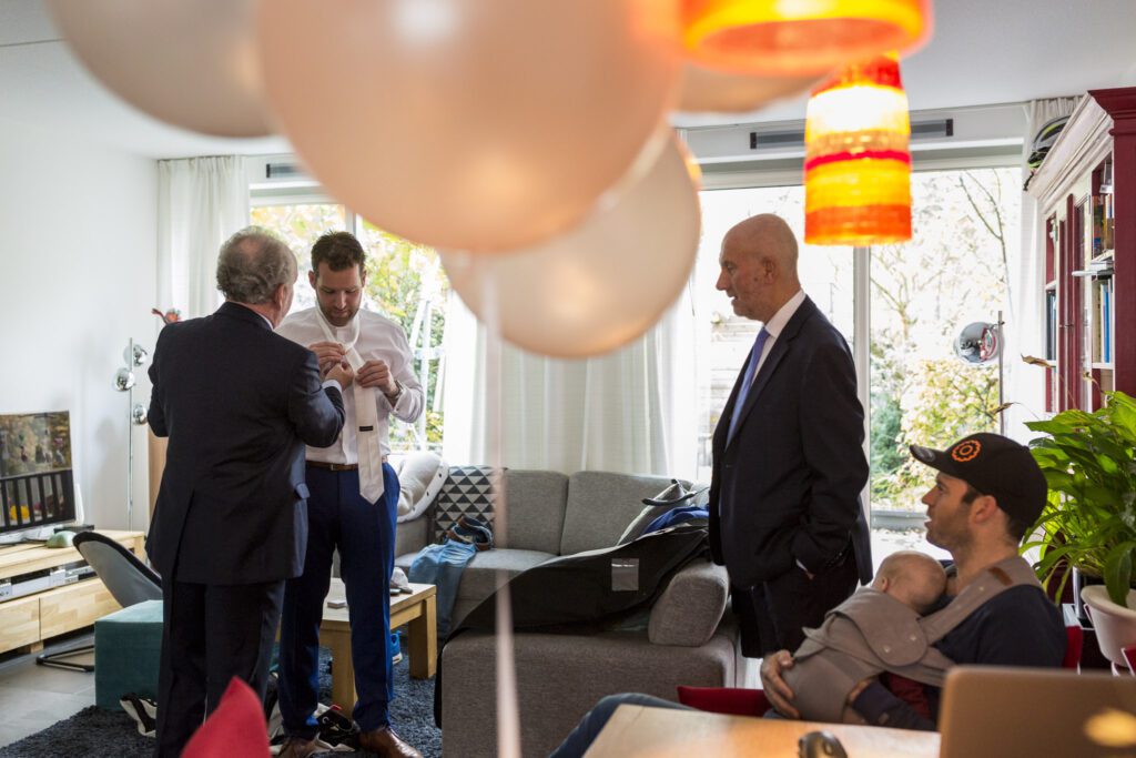 Mannen helpen bruidegom met het strikken van zijn stropdas.