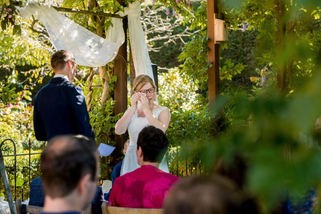 Bruid droogt haar tranen van ontroering tijdens de ceremonie.