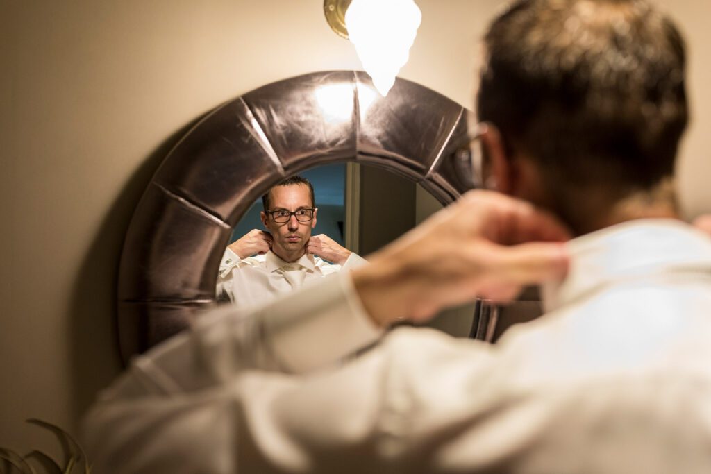 Bruidegom trekt voor de spiegel zijn blouse aan.