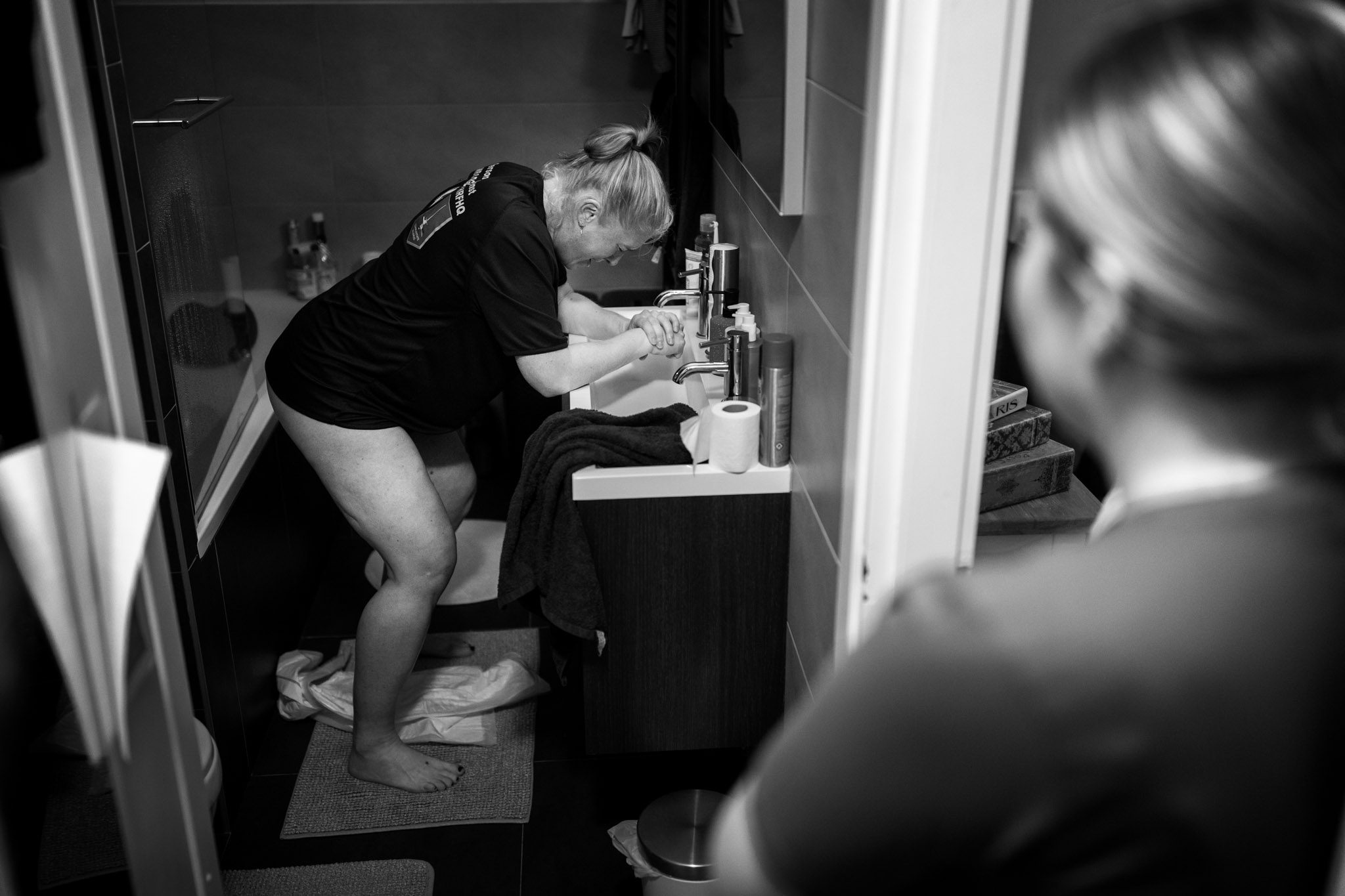 Vrouw vangt weeën op terwijl de verloskundige toekijkt