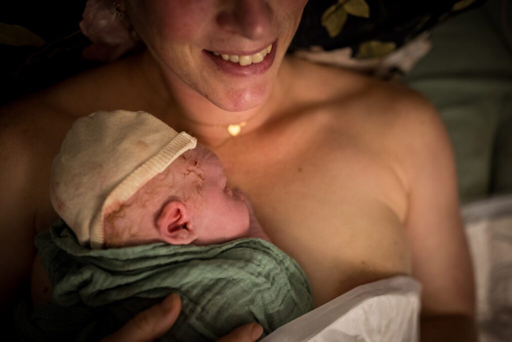 Baby ligt op de borst van mama bij te komen na de bevalling