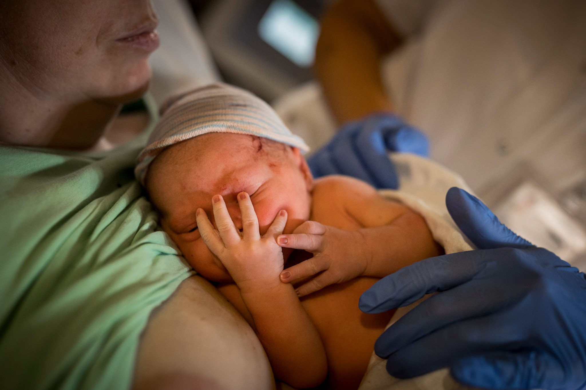 Pasgeboren baby duimt terwijl ze bij mama ligt