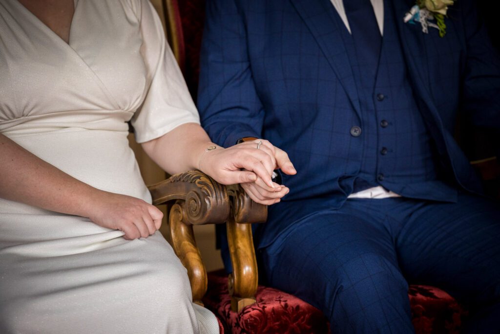 Close-up van de handen van een bruidspaar tijdens de ceremonie.