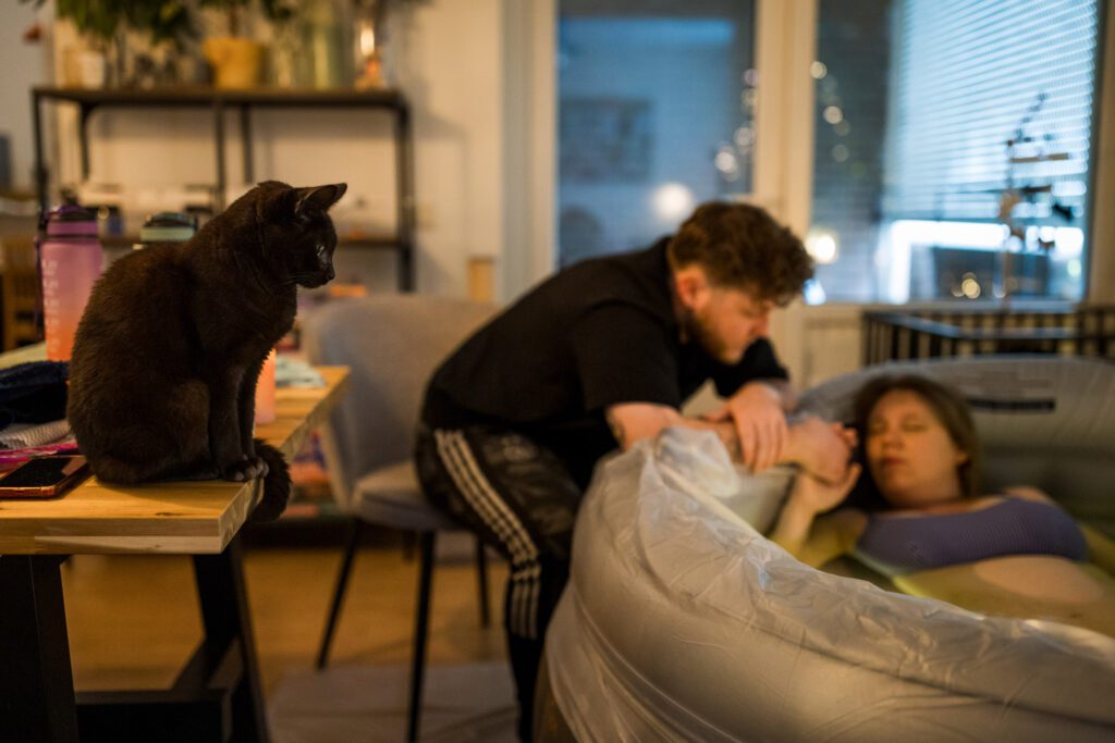 Kat en man kijken naar vrouw in bevalbad