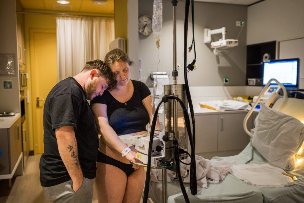 Man en vrouw leunen op elkaar bij een ziekenhuisbevalling