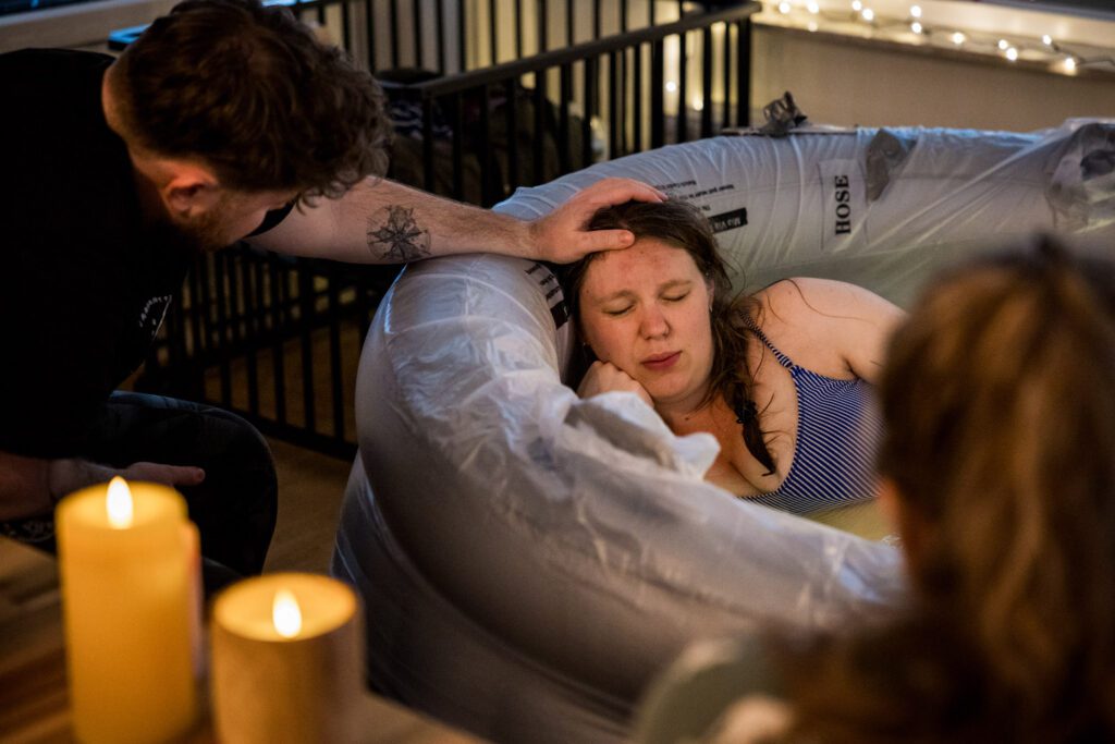 Man ondersteunt bij bevallende vrouw in het bevalbad