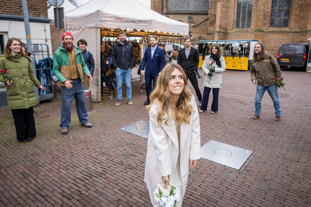 Bruid gooit bruidsboeket op een marktplein.