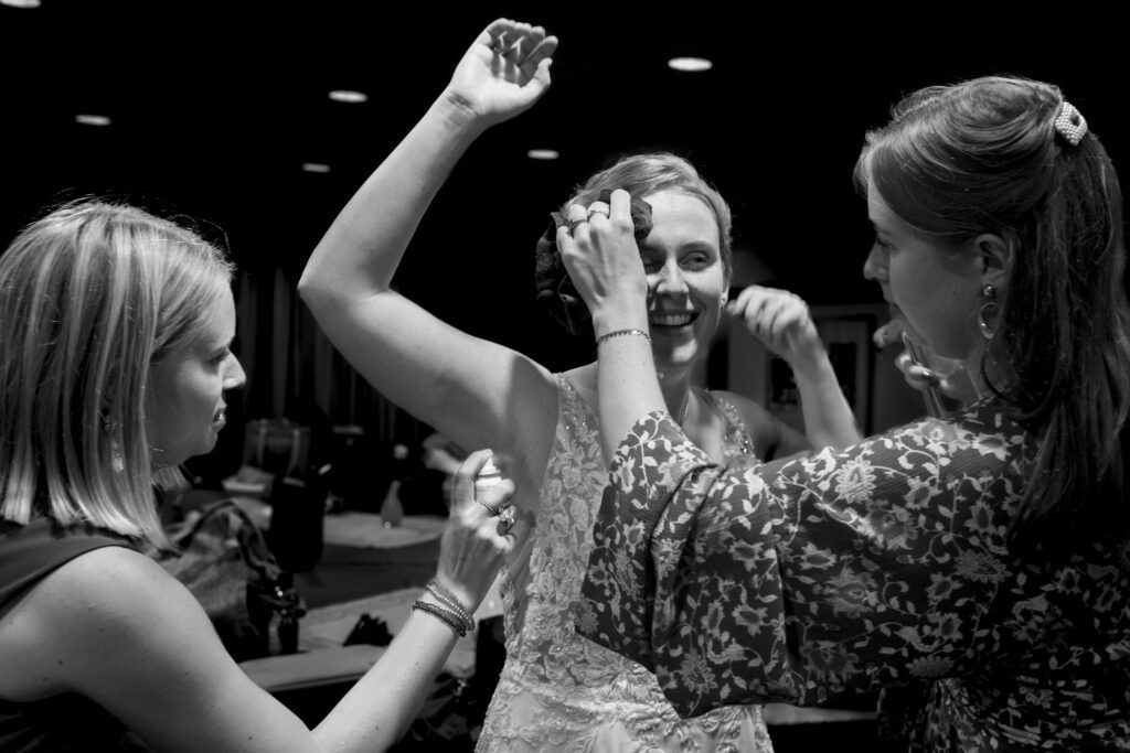 Bruid wordt voor het bruidsfeest opgefrist door haar bruidsmeisjes.