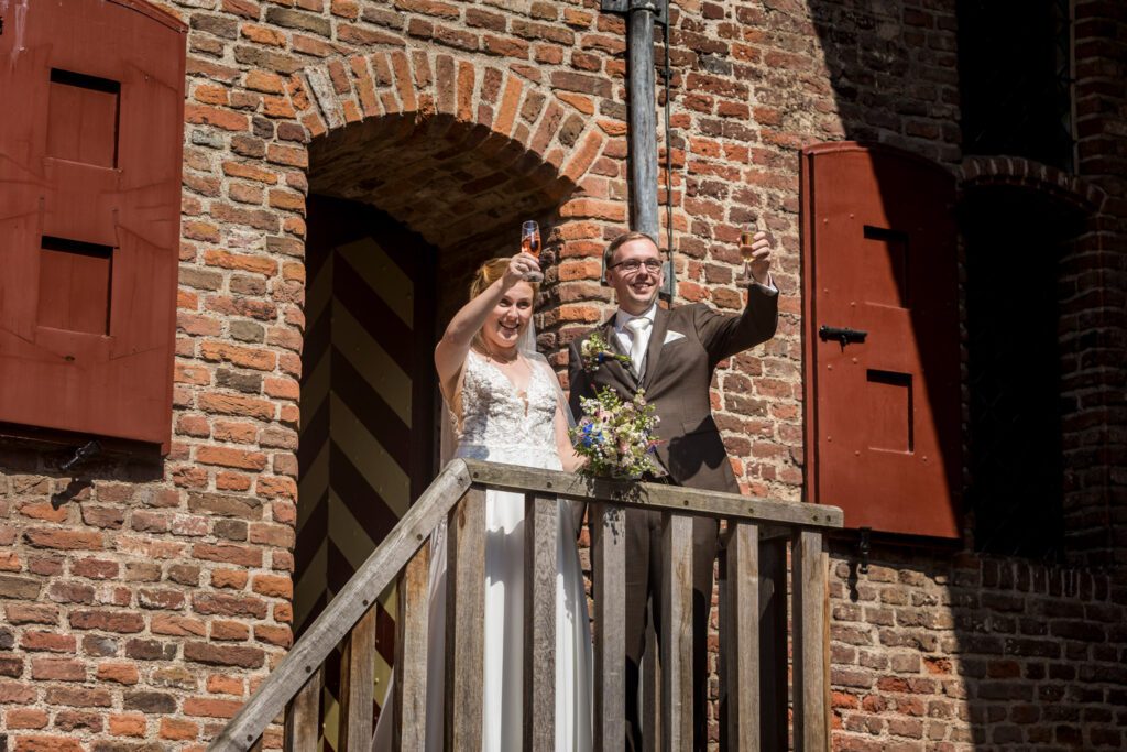 Bruidspaar proost vanaf het balkon van Kasteel Hernen.