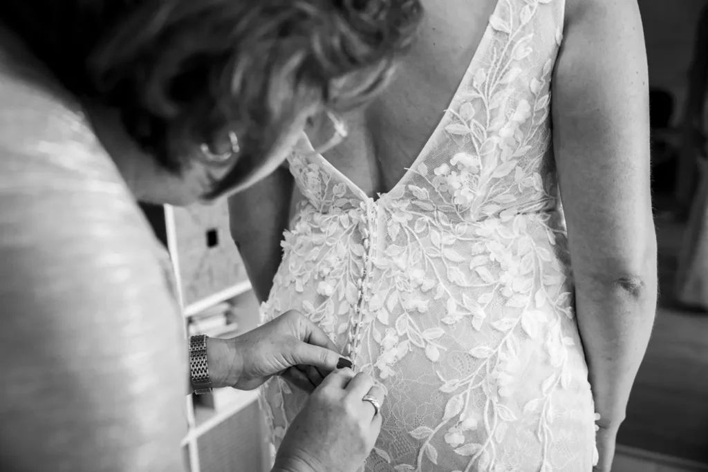 Moeder van de bruid sluit de bruidsjurk.