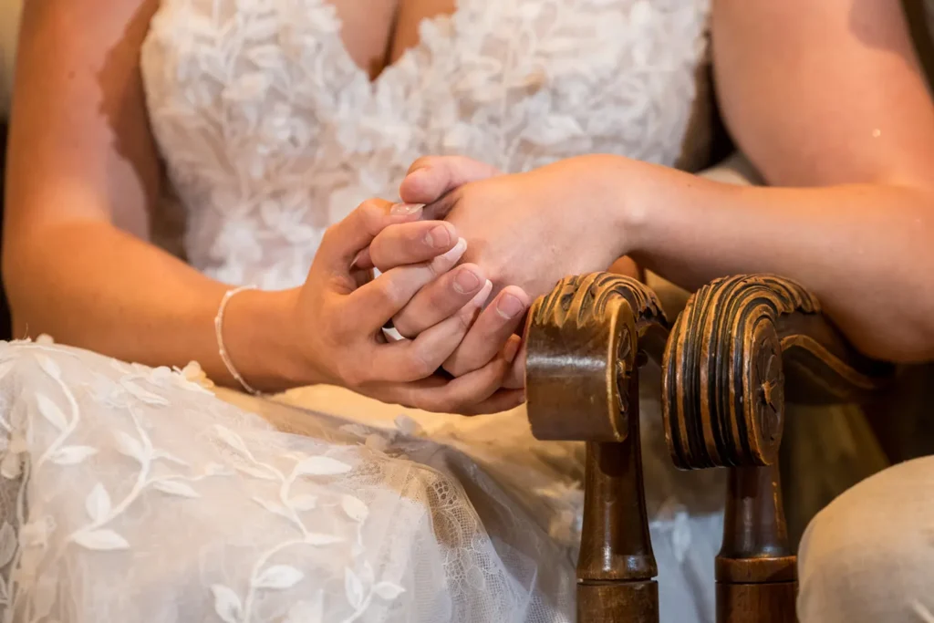 Close-up van een bruidspaar dat handen vasthoudt.