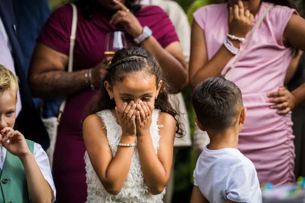Jonge bruiloftsgast lacht in haar handen.