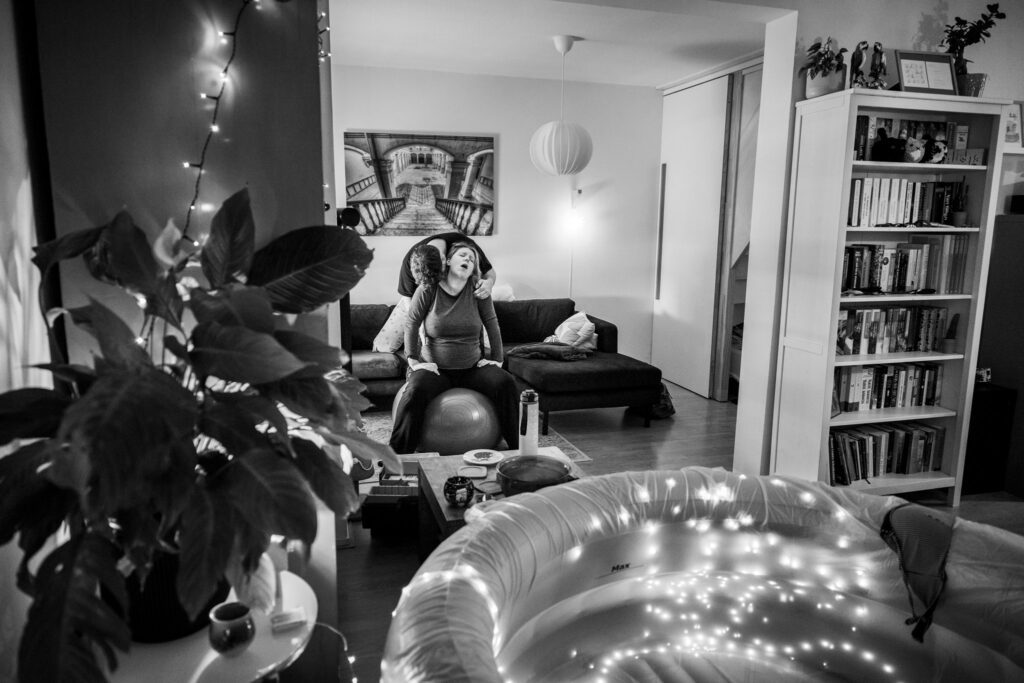 Man ondersteunt vrouw bij het opvangen van een wee met bevalbad op de voorgrond