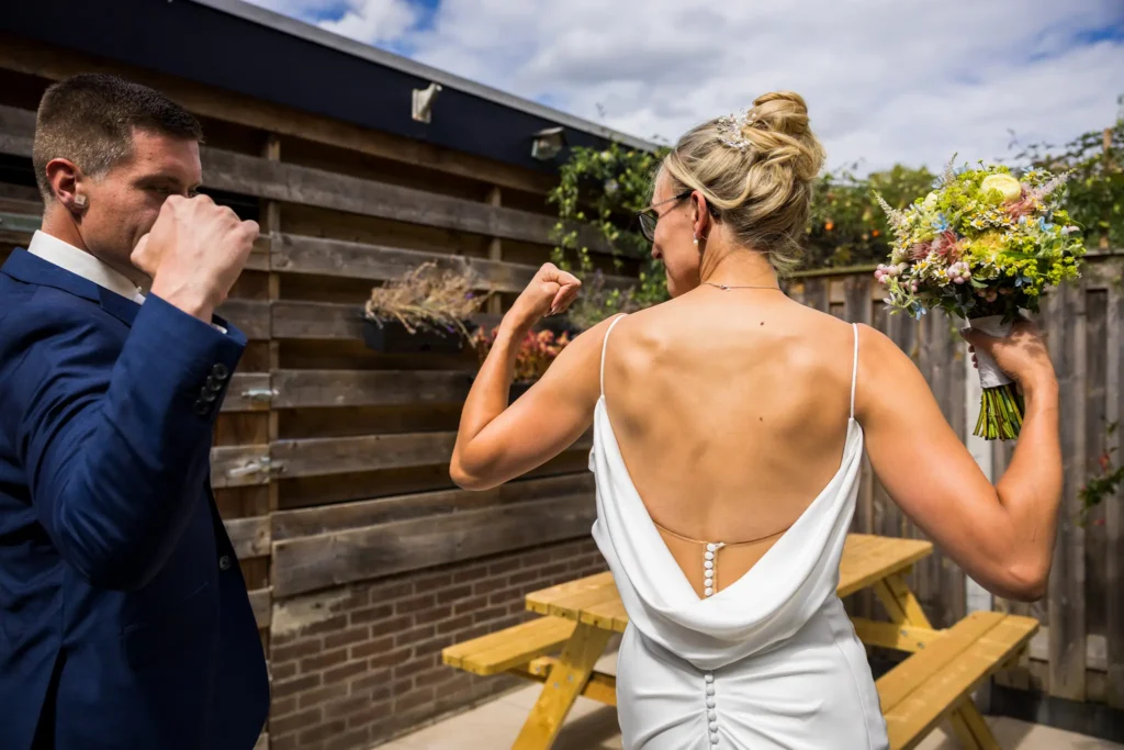 Bruid en bruidegom laten spierballen zien in hun trouwkleding.