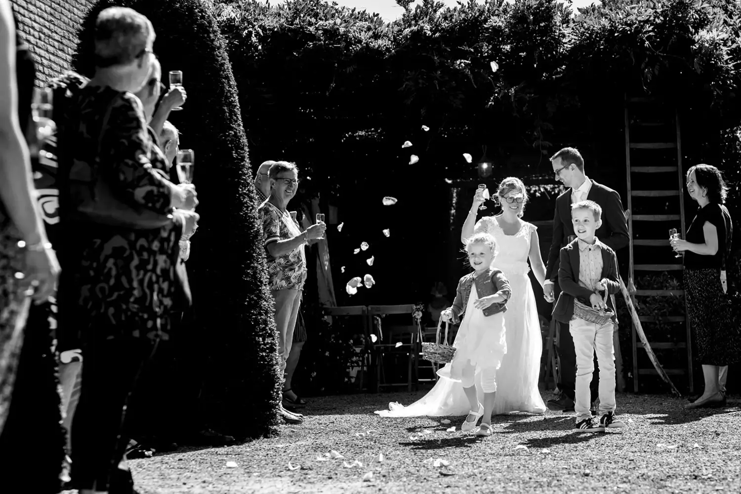 Gasten gooien rozenblaadjes naar het bruidspaar