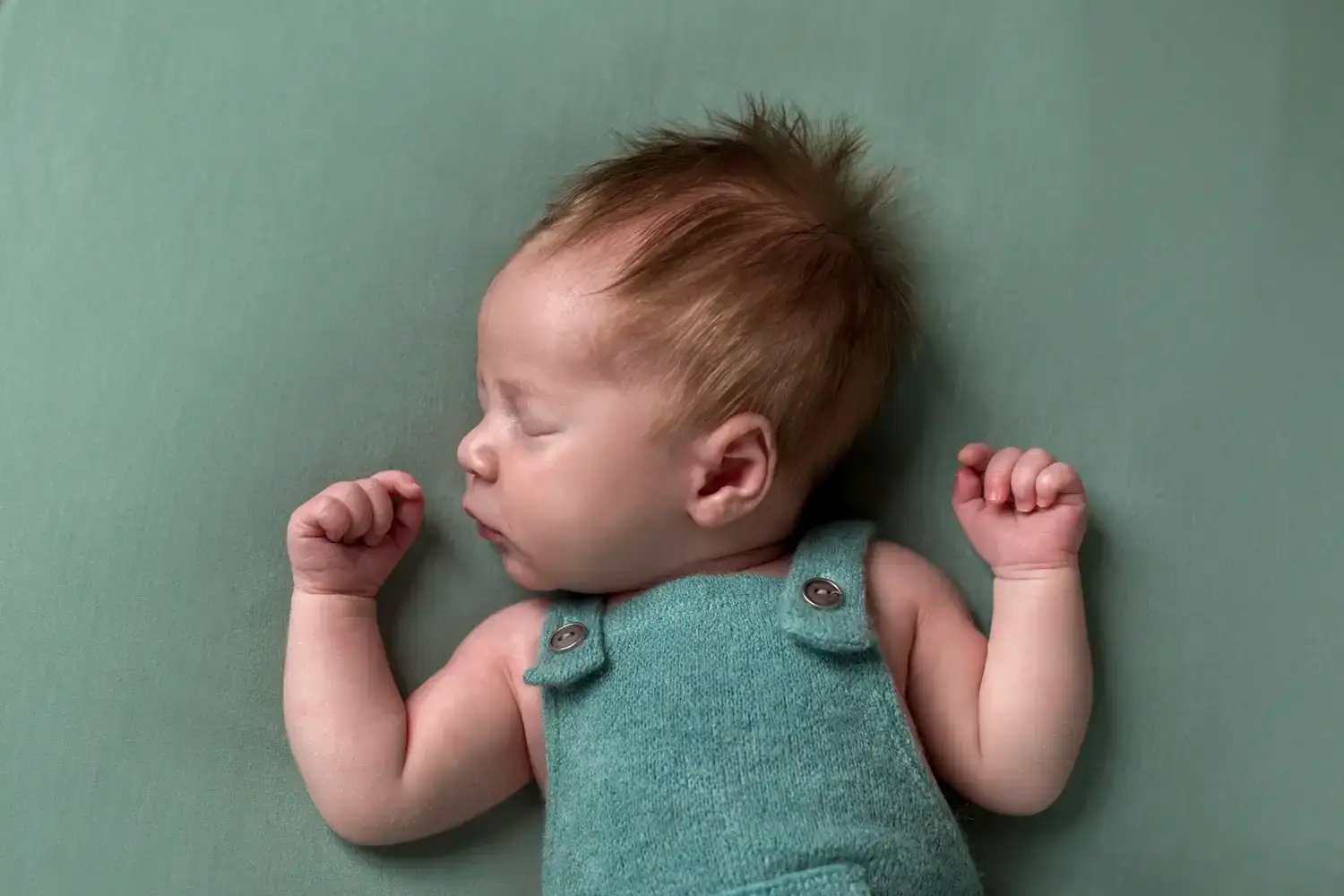 Baby slaapt op zijn rug tijdens de newbornshoot.