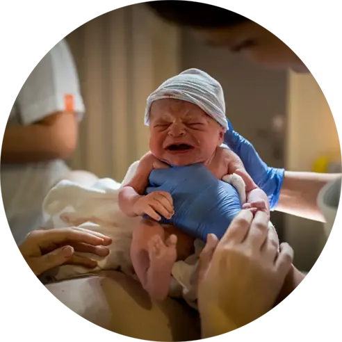 Verloskundige toont pasgeboren baby aan de moeder.