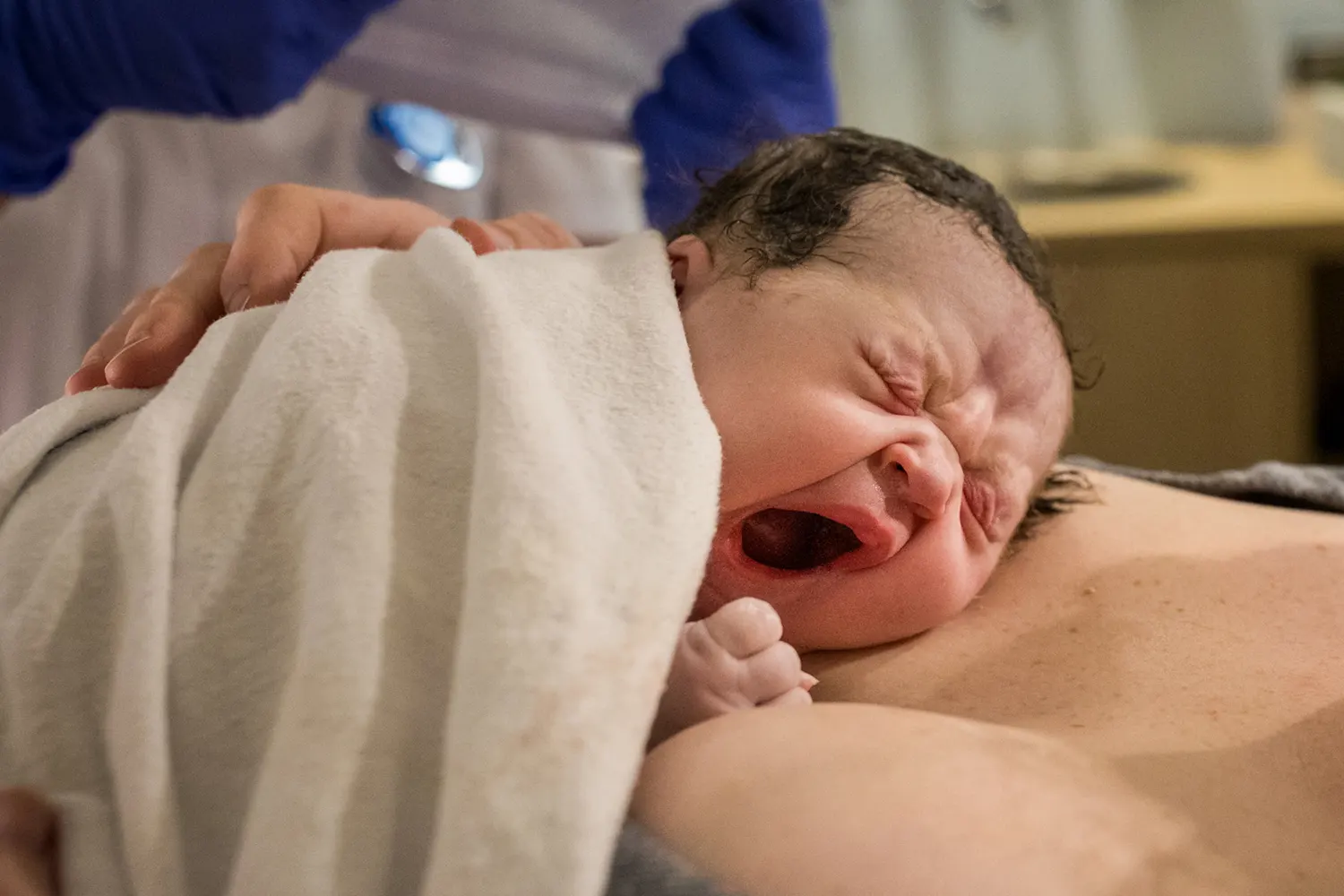 Pasgeboren baby gaapt terwijl ze op de borst van haar moeder ligt.