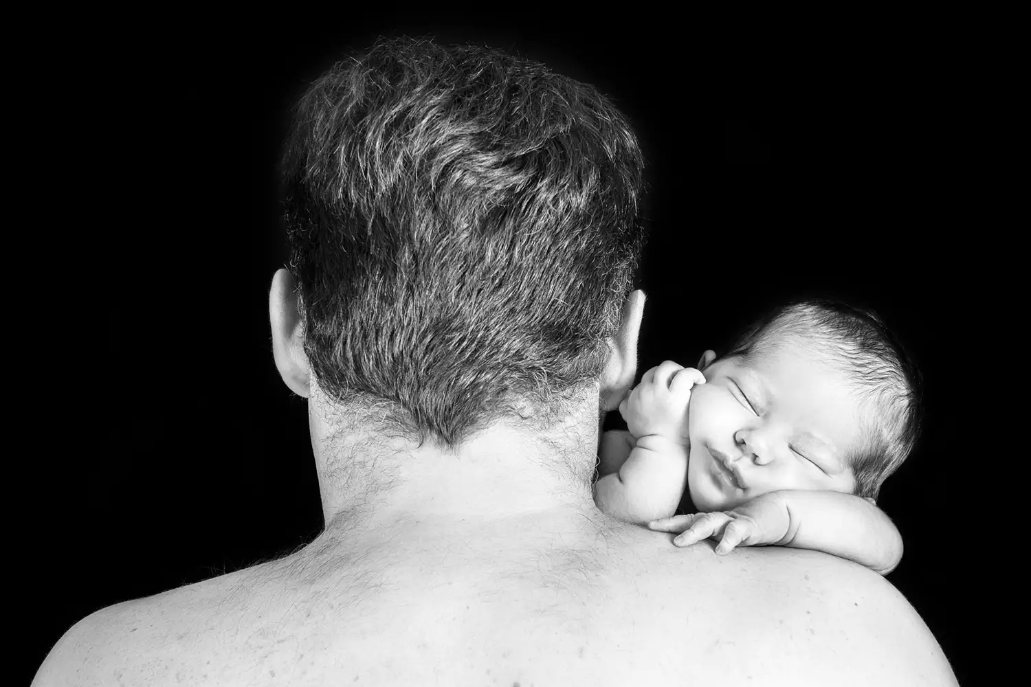 Baby slaapt op de schouder van zijn vader.