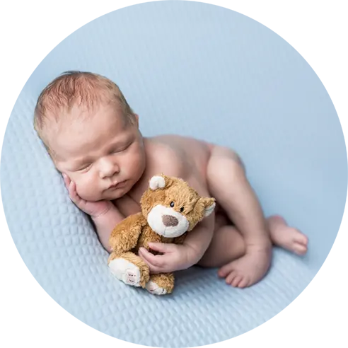 Baby slaapt met een beertje in de hand tijdens de newbornshoot