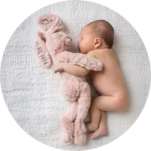 Baby slaapt met een knuffel tijdens haar newbornshoot.