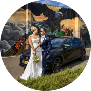 Bruifdpaar kijkt naar elkaar terwijl ze tegen een auto leunen