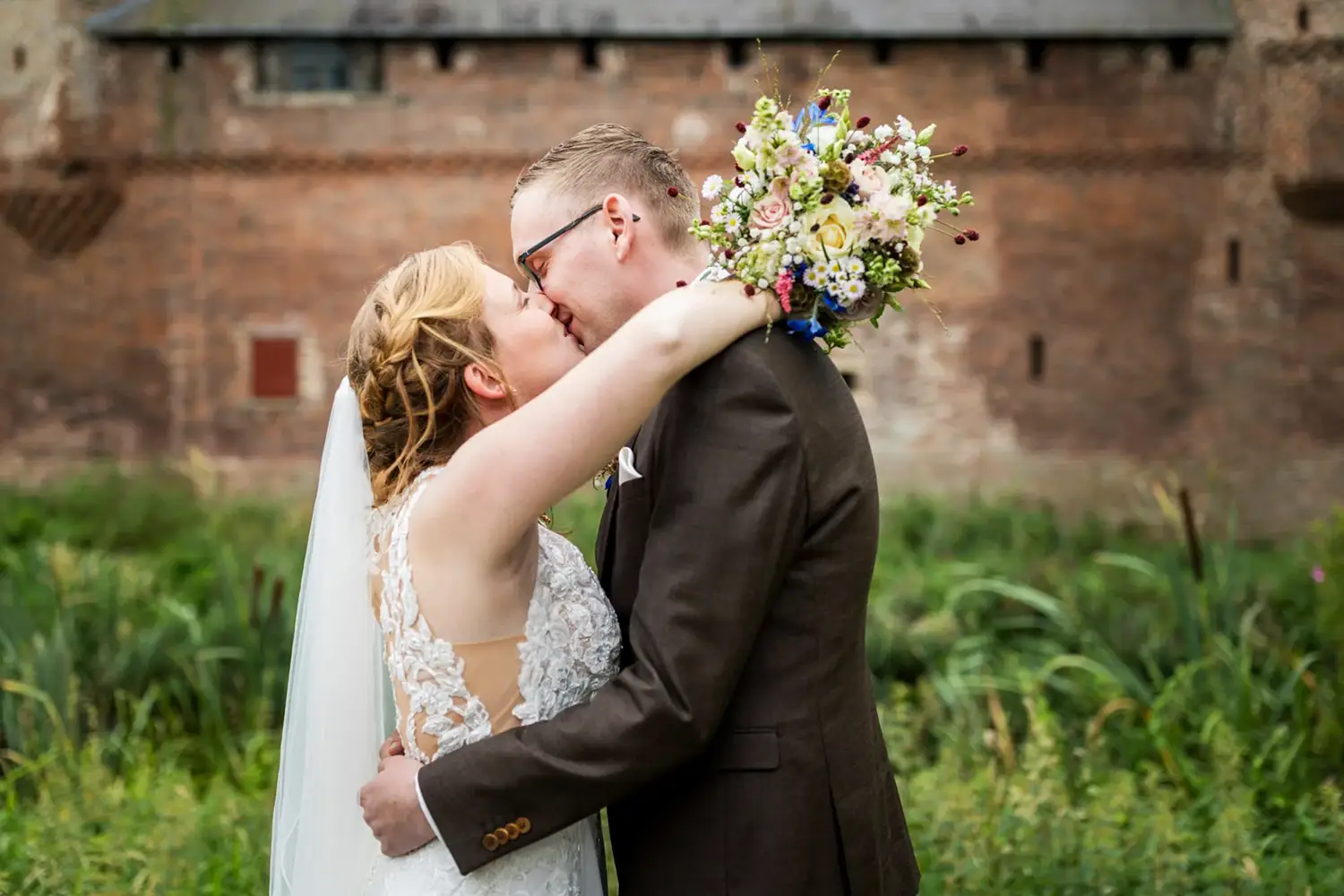Bruidspaar kust elkaar voor Kasteel Hernen