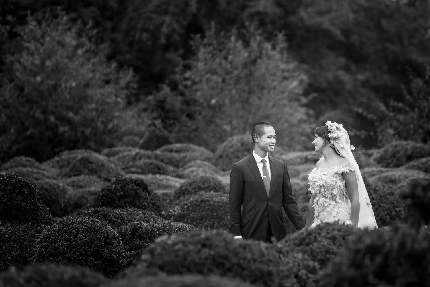 Bruidpaar kijkt naar elkaar terwijl ze handen vasthouden.