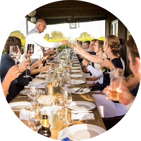 Bruiloftsgasten proosten aan een lange tafel