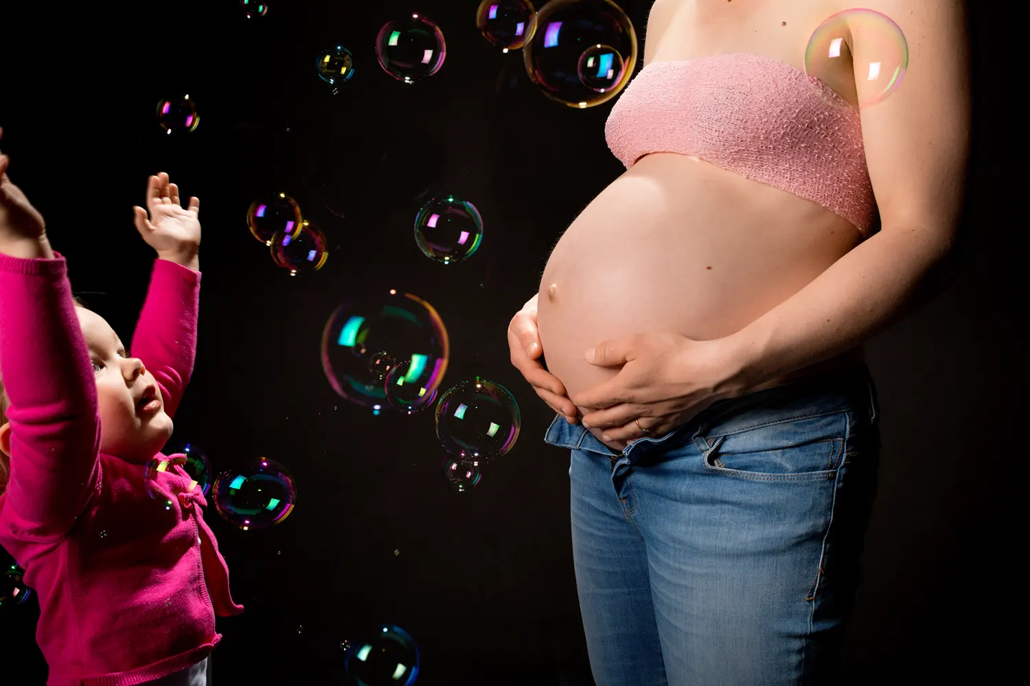 Meisje probeert zeepbellen te vangen tijdens een zwangerschapsshoot